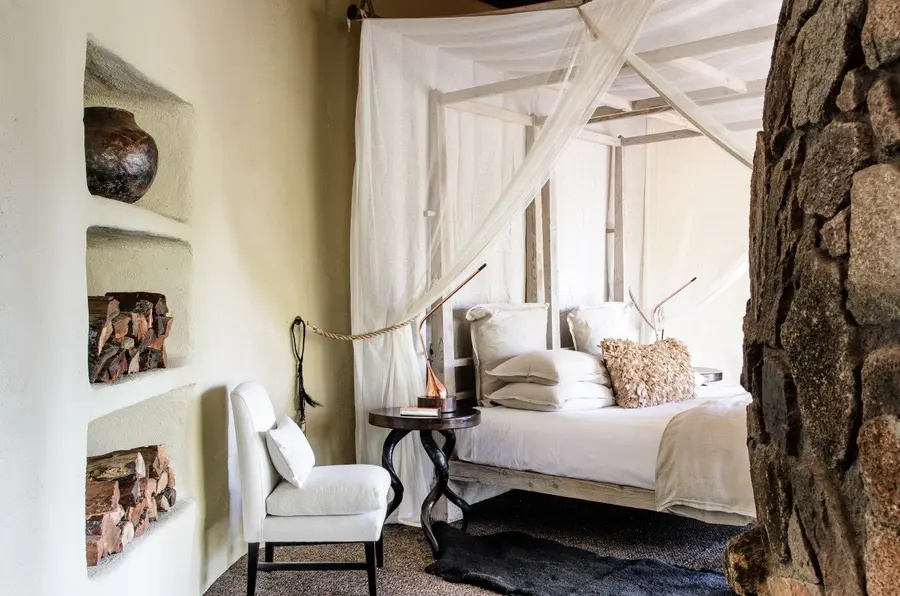 Singita Boulders Lodge_River Suite Bedroom with white chair_Adriaan Louw