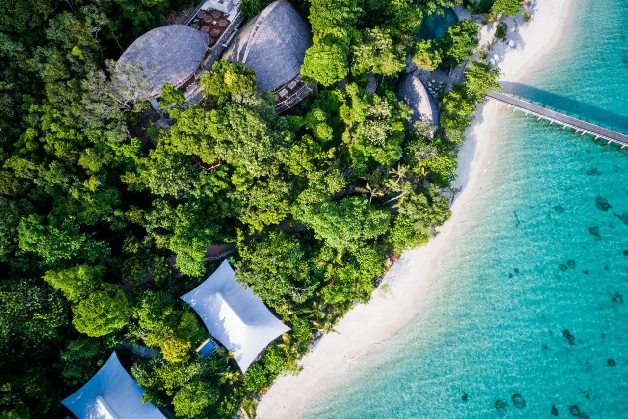 aerial_beach_suites_next_to_jetty_&_treetops_with_green_forest_background