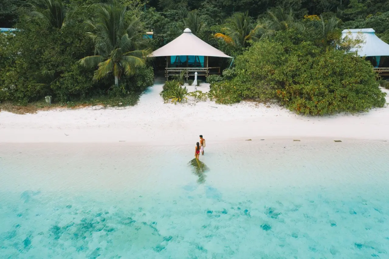 young_couple_in_lagoon_walking_to_beach_suite