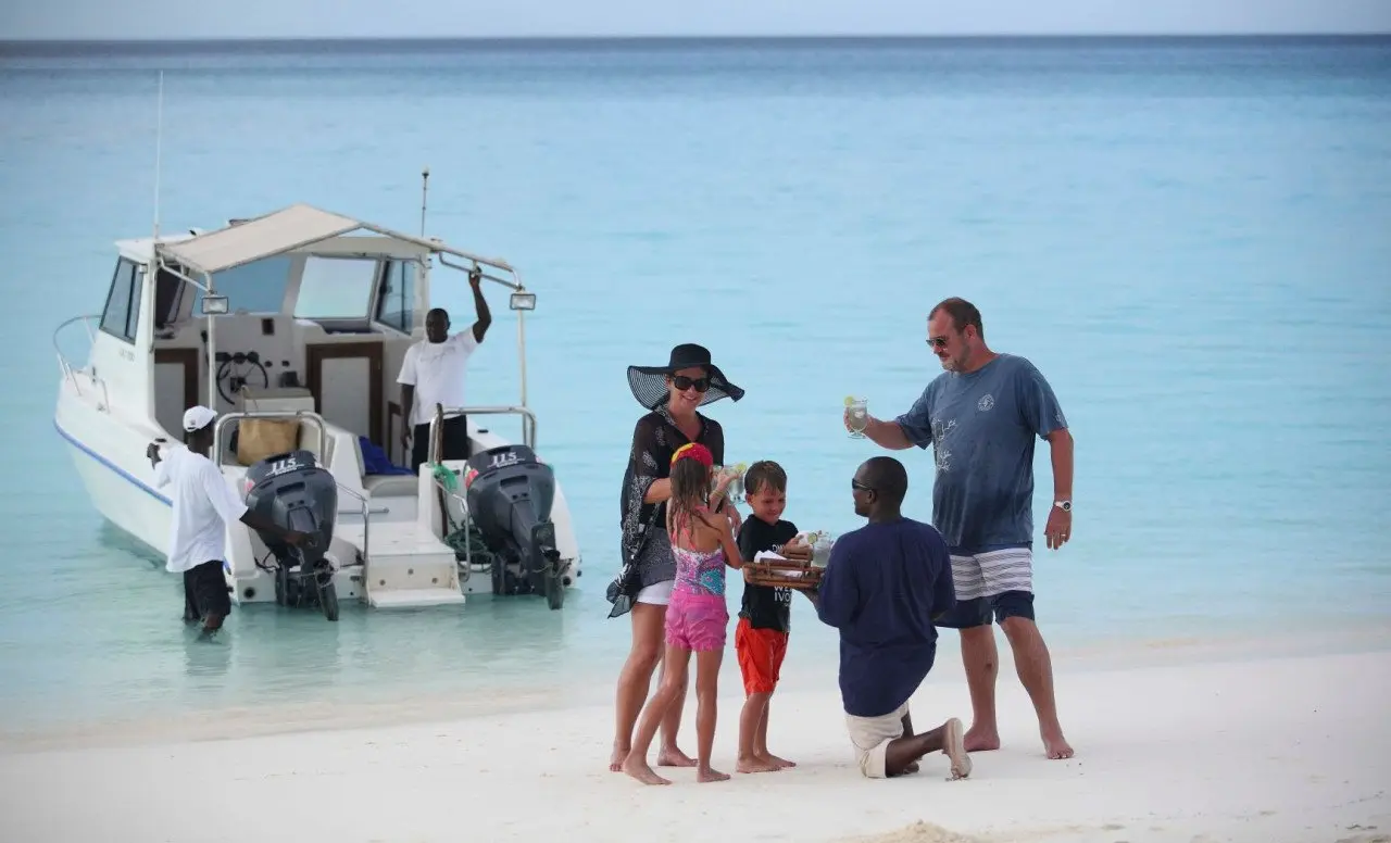 Zanzibar-Mnemba-island-Arrival-family-greeting-butler-on-the-beach-02