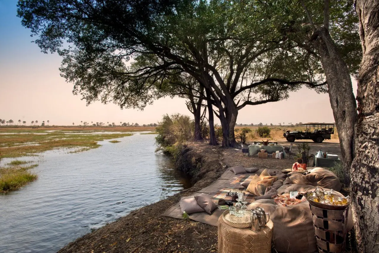 Botswana-Sandibe-Guest-delight-lunch-by-the-river-with-vehicle