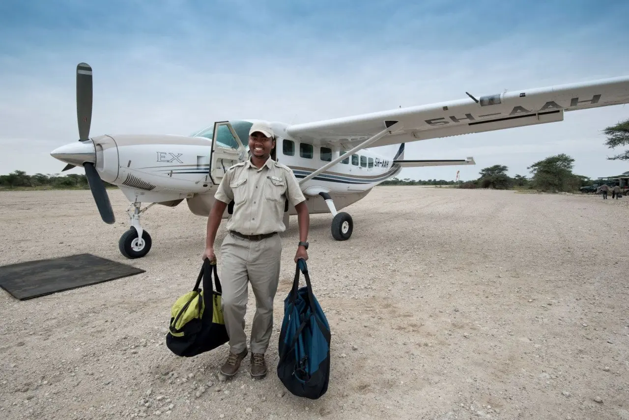 Tanzania-Serengeti-Under-Canvas-SUC-Guest-Area-Arrival-plane-with-andBeyonder-staff-carrying-luggage