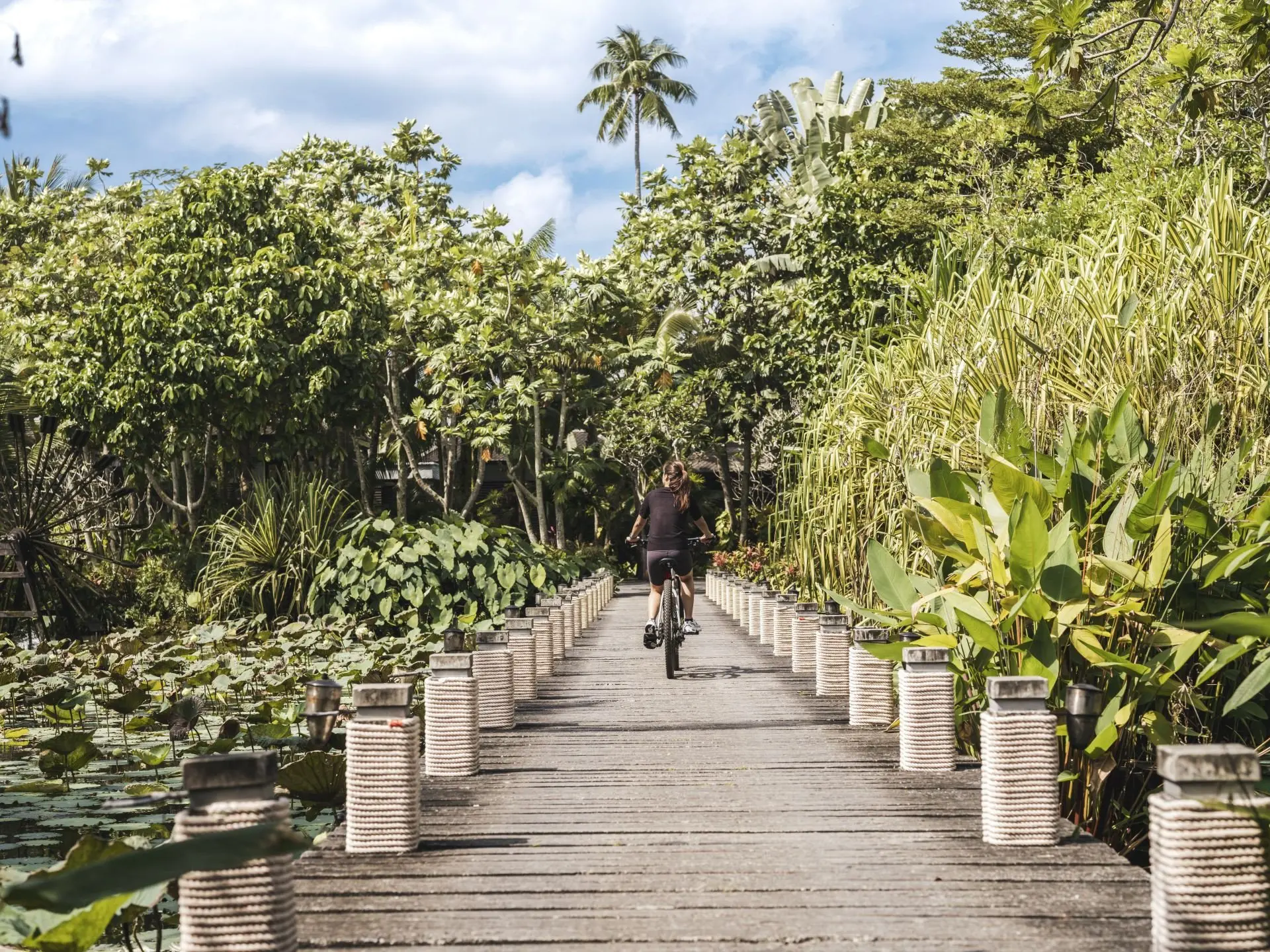 small_Anantara_Mai_Khao_Phuket_Villas_Exterior_View_A_Woman_Rides_A_Bike_Over_The_Bridge