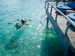 close_up_backview_young_couple_clear_kayaking_in_lagoon_under_overwater_suite_sun_terrace
