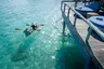 close_up_backview_young_couple_clear_kayaking_in_lagoon_under_overwater_suite_sun_terrace